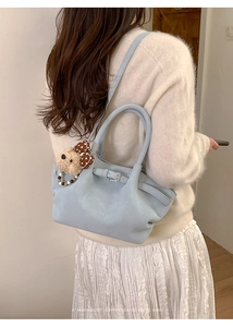 Bolso tipo cubo de cuero azul claro con dije de osito de peluche y asa de cuentas en modelo