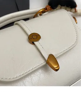 Détail du sac bandoulière blanc texturé avec fermoir doré et poignée de perles chic