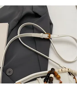 Détail de la bandoulière réglable et poignée en perles de bois du sac blanc