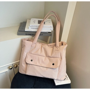 Detail view of pink quilted tote bag with front flap pocket and wide shoulder strap