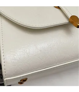 Gros plan du sac à main en cuir blanc vintage avec fermoir doré et coutures fines