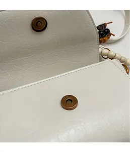Détail du sac en cuir crème grainé avec fermoir en métal vintage et bandoulière perlée