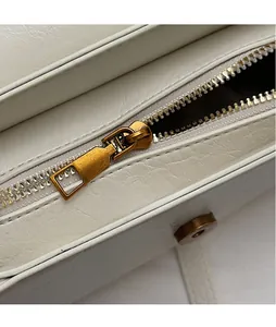 Détail de la fermeture éclair dorée et du fermoir magnétique sur un sac à main blanc