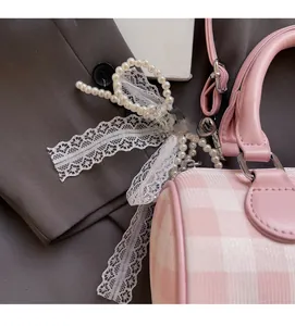 Vue détaillée du sac à carreaux roses avec perles élégantes et nœud en dentelle blanche