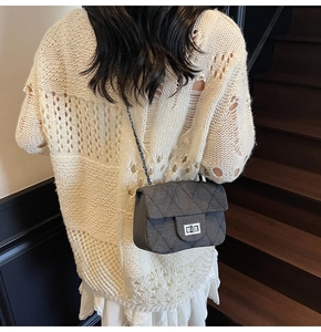 Detail of grey quilted crossbody bag with silver metal turn-lock and chain strap