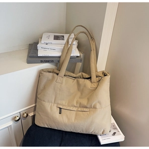 Detail of khaki puffer tote bag with front zipper pocket on a cozy minimal background