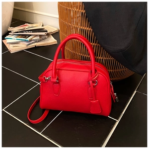 Dettaglio borsa bowling in pelle rossa a grana litchi con finiture argentate e manici