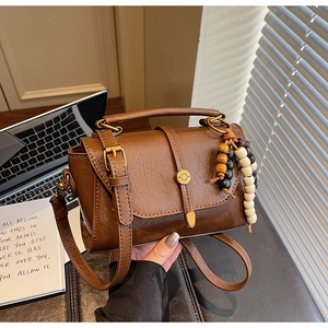Détail du sac rétro marron en cuir huilé avec pendentif en perles de bois