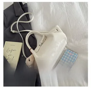White pleated bucket bag with bear pendant shown next to professional business accessories