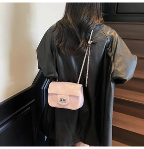 Close-up of a pink quilted chain bag with a silver twist lock on a black leather jacket