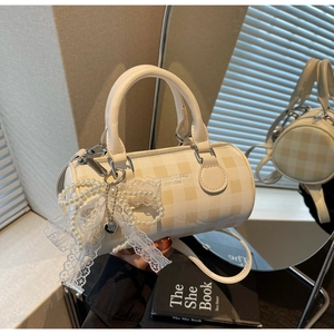 Détail du sac baril à carreaux avec breloque en dentelle de perles et logo YAXICI