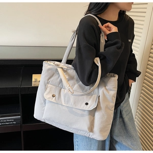 Detail of the large capacity grey canvas tote bag with front flap pocket and metal snaps