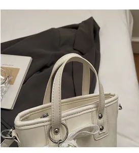 Dettaglio del manico in pelle martellata e fiocco di pizzo su borsa crema PU