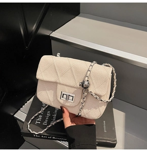 Detail of cream quilted chain bag featuring silver twist lock and adjustable metal ball