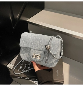 Detail of light blue denim crossbody bag with diamond stitching and chain strap