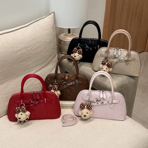 Group of textured matte Boston bags with bear charms on a sofa in a warm setting