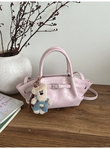 Pink PU leather bucket bag detail with decorative belt buckle and cute teddy bear charm