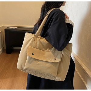 Side view of a beige canvas tote bag with large snap-button pockets on a female model