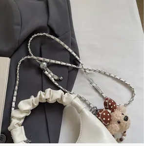 Detail of white pleated cloud bag featuring silver chain strap and plush bear charm