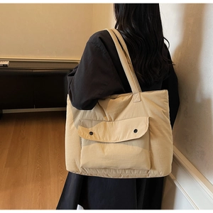 Detail shot of the large beige tote bag showing its durable fabric and front button pockets
