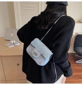 Detail of tweed crossbody bag featuring silver chain strap and metal turn-lock closure
