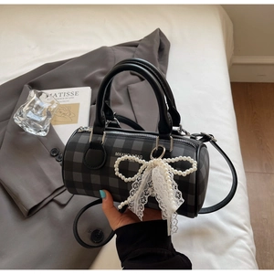 Détail d'un sac Boston à carreaux gris avec nœud en dentelle perlée et bandoulière