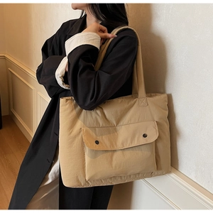 Detail of khaki tote bag with dual snap buttons on the front pocket shown on shoulder