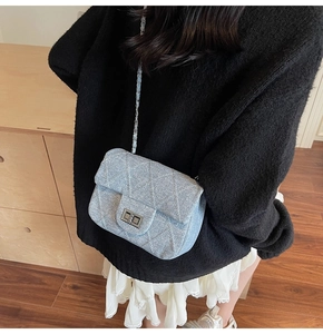 Detail of light blue glitter quilted chain bag with silver twist-lock and denim texture