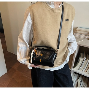 Détail du sac bandoulière vintage noir texturé avec breloque et boucle dorée