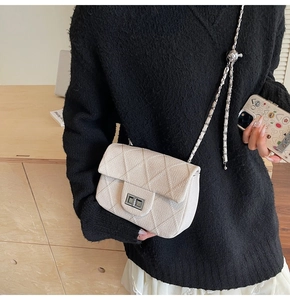 Detail of quilted tweed flap bag with silver rotary lock and adjustable chain strap