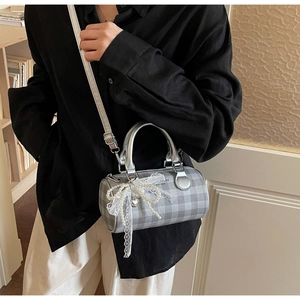 Détail du sac baril à carreaux argentés avec nœud en dentelle et chaîne de perles