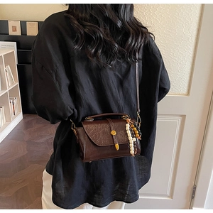 Détail du sac bandoulière vintage marron foncé avec perle en bois et rabat aimanté