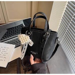 Detail der schwarzen Beuteltasche mit Perlenherz-Anhänger und Spitzenband-Deko