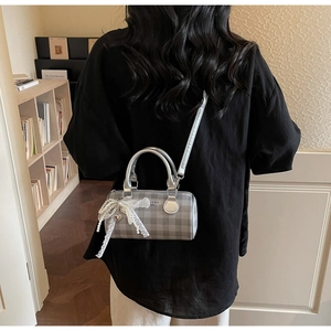 Détail du sac cylindre argenté à carreaux gris avec nœud en dentelle et perles chic