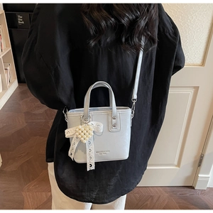 Details einer hellblauen Mini-Beuteltasche mit Spitzenschleife und Perlenherz-Anhänger