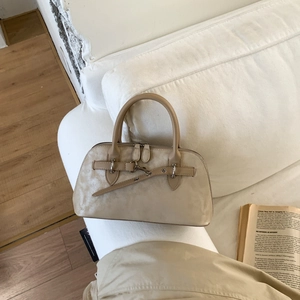 Close-up of a minimalist beige matte leather handbag on a soft white sofa in a lifestyle setting