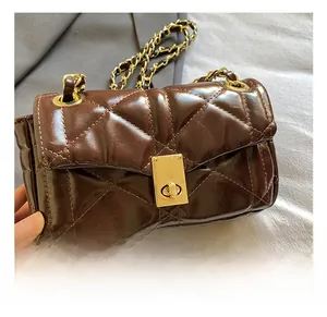 Close-up of golden metal lock and quilted leather detail on brown crossbody chain bag