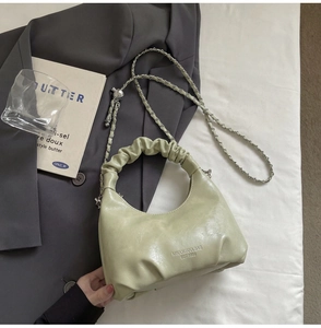 Detail of pistachio green hobo bag featuring pleated handles and silver chain strap