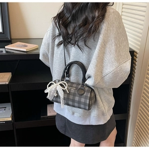 Detail of checkered barrel bag with white lace bow and detachable shoulder strap