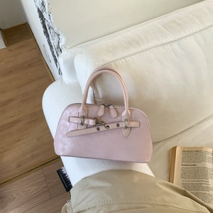 Pink matte leather Boston bag with decorative strap and silver buckle on a white sofa