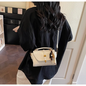 Vue détaillée d'un sac à bandoulière en cuir blanc avec accessoire de perles en bois