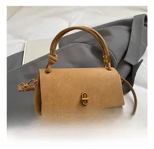 Detail of camel suede crossbody bag featuring gold buckle and knotted handle detail