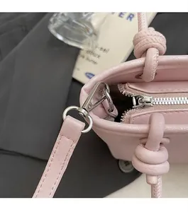 Vue macro du cuir grainé rose avec des ferrures argentées et détail de poignée nouée