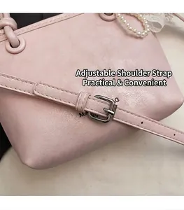 Gros plan sur la bandoulière réglable en cuir rose avec boucle argentée et couture fine