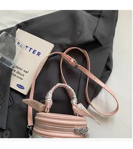 Détail d'un sac seau rose cylindrique avec foulard en soie décoratif sur l'anse