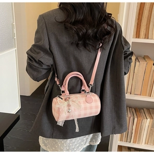 Detailed view of pink plaid cylinder bag with pearl chain and bow on gray blazer