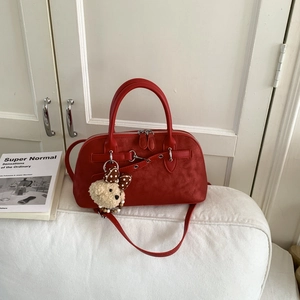 Detail of red frosted leather bowling bag with silver hardware and plush bear charm