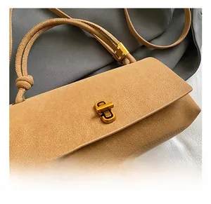 Detail of premium khaki suede bag featuring a luxurious gold metallic twist-lock closure