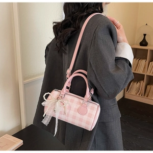 Gros plan du sac Boston à carreaux roses avec nœud perlé et ruban de dentelle