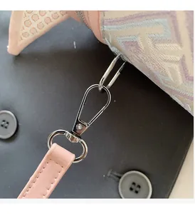 Détail de la boucle en métal argenté et de la bandoulière en cuir rose du sac seau jacquard